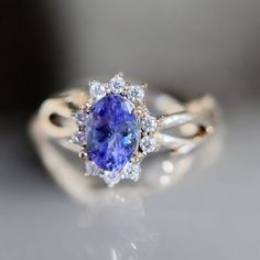 a tan and white gold ring with a blue sapphire surrounded by diamonds on a gray surface