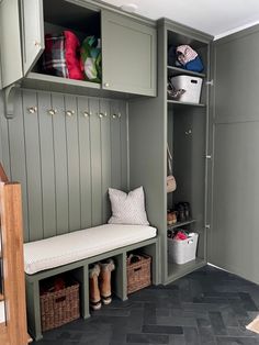 a mud room with gray cabinets and white pillows on the bench next to the entryway