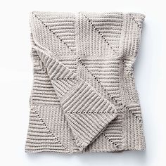 a knitted blanket folded on top of a white surface with an open square in the middle