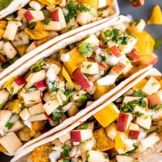 two tacos on a plate with fruit and cilantro