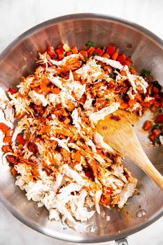 the food is being cooked in the pan with a wooden spoon on the side and ready to be eaten