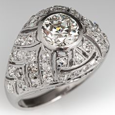 an antique style diamond ring with filigrees on the sides and round brilliant cut diamonds in the center