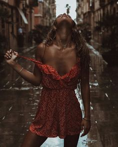 a woman standing in the rain holding an umbrella and looking up into the sky with her eyes closed