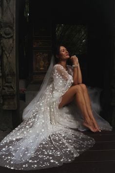 a woman in a wedding dress sitting on the ground with her legs crossed and wearing a veil