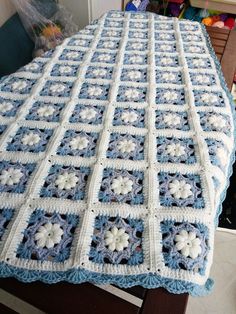 a blue and white crocheted blanket sitting on top of a table