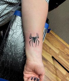 a woman's arm with a spider tattoo on it