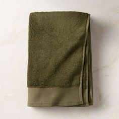 a folded green towel sitting on top of a white counter