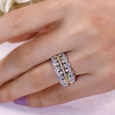 a woman's hand with a diamond ring on top of her finger and flowers in the background