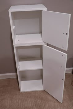 a white bookcase with two doors open on the floor in front of a wall