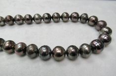 a close up of a black pearl necklace on a white surface with space for text