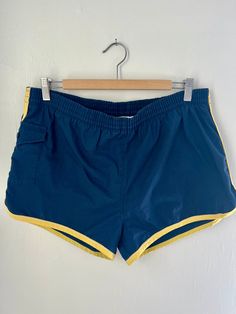 1970/1980s men's swim trunks in excellent vintage condition!  Navy blue dolphin style swim trunks with yellow trim on sides and edges. Working button closure  pocket on side. Tiny secret pocket on inside front. Non rips, stains or tears! Size 36-38 - modern Large/XL Vintage Swim Trunks, Blue Nylon Short Swim Trunks, Retro Swim Trunks With Built-in Shorts, 1980s Men, Yellow Swim Trunks With Built-in Shorts, 1970s Men, Orange Swim Trunks With Built-in Shorts, Blue Dolphin, Yellow Trim