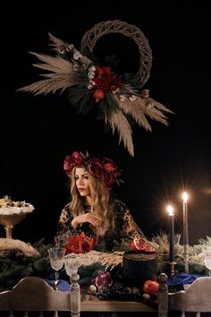 a woman sitting at a table with candles in front of her and an angel above her head