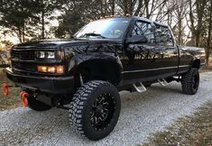 a black truck parked on top of a gravel road