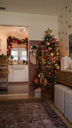 a decorated christmas tree in a kitchen next to a living room and dining room area