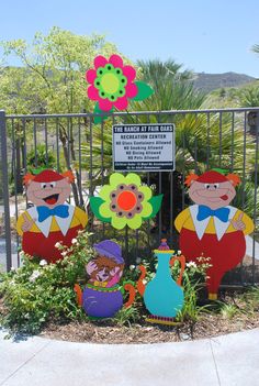 a group of paper cut outs sitting in front of a fence with flowers on it