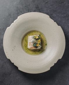 a white plate topped with food on top of a gray countertop next to a knife and fork