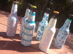 six painted bottles sitting on top of a wooden table