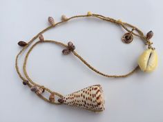 Shell jewelry or " Solo shell talisman " En Forme d' idées is a unique piece (Deposited model), made with ❤️ . This summer jewel is made of light brown braided natural fiber. The washable natural fiber is braided with a golden thread and assembled with a conical shaped shell pendant and small shells punctuating the braiding. This natural fiber is very beautiful and very pleasant to wear. Natural fiber braided clasp with cowrie shell. *✨Little bag made in India 🙏 Shell jewelry is a trendy and ti Handmade Shell Pendant Necklace For Beach, Unique Shell Jewelry For The Beach, Unique Shell Jewelry For Beach, Handmade Pendant Shell Necklace For Beach, Artisan Adjustable Shell Necklace For The Beach, Artisan Shell Jewelry For The Beach, Adjustable Long Necklace For Beach, Handmade Shell Necklace For Beach, Unique Handmade Shell Necklace For Beach