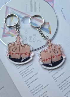 two keychains with the same image on them, one has a hand holding a heart