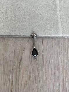 a black and white necklace on a wooden floor next to a gray wall with a silver chain