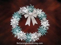 a paper snowflake wreath on a wooden table with white ribbon and silver bow