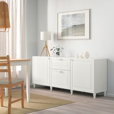 an empty room with white furniture and a painting on the wall above it's desk