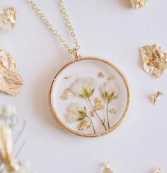 some white flowers are in a glass and gold necklace