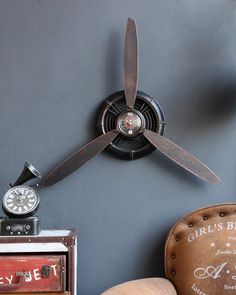 a ceiling fan mounted to the side of a wall next to a chair and clock