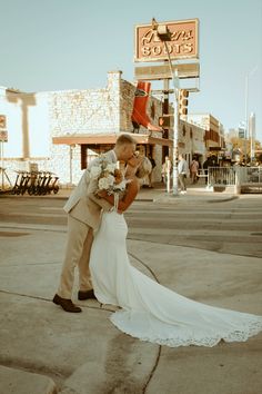 a bride and groom kissing on the street