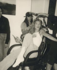 black and white photograph of three women sitting in an office chair with bicycles on the wall behind them