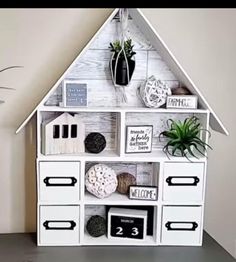 a white shelf with some plants and pictures on it