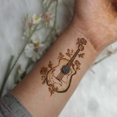 a woman's wrist with a guitar tattoo on it