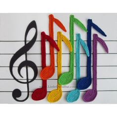 crocheted musical notes are lined up on a sheet of paper