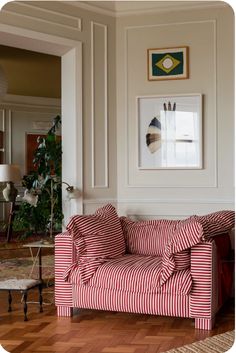 a red and white striped couch sitting in a living room next to a painting on the wall