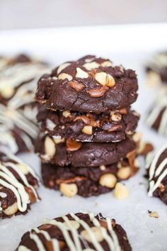 chocolate cookies are stacked on top of each other with white and brown drizzles