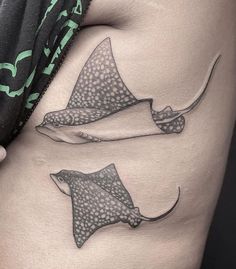 a woman's stomach with two stingfish tattoos on it