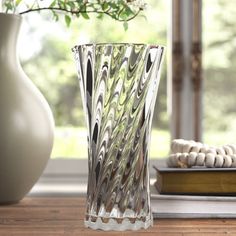 a glass vase sitting on top of a wooden table next to a book and flowers