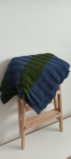 a blanket sitting on top of a wooden stool next to a white wall and floor