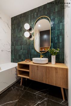 a bathroom with marble walls and green tiles on the wall, along with a wooden vanity topped with a round mirror