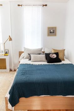 a bedroom with white walls and wood flooring has a blue blanket on the bed