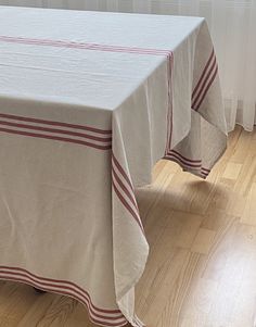 a white table cloth with red stripes is on the floor in front of a window