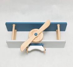 a wooden toy airplane is hanging on the side of a white and blue shelf with two pieces of wood attached to it