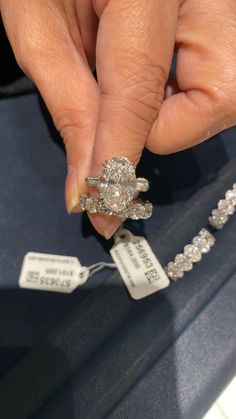 a woman's hand holding a diamond ring in front of a jewelry store display