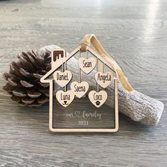 a wooden house ornament with hearts hanging from it's side on a table next to a pine cone