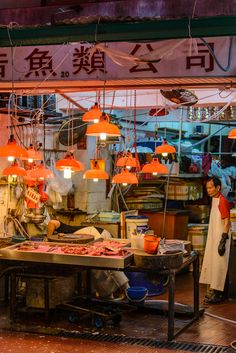 a man standing in front of a fish market with lots of lights hanging from the ceiling