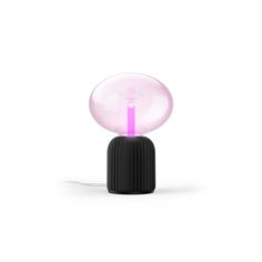 a pink light sitting on top of a black table next to a white wall and floor