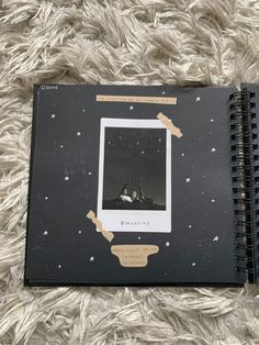 an open notebook with pictures on it sitting on top of a white carpeted floor