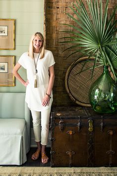 a woman standing in front of a trunk with a green vase on top of it