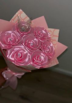 a bouquet of pink roses with a tiara on top is being held by someone's hand