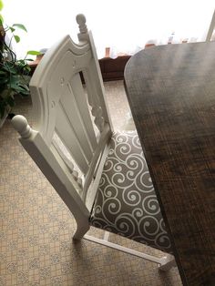 a wooden table sitting next to a white chair on top of a tile covered floor